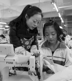 大英縣中等職業技術學校內，企業服裝技師正指導學生進行縫紉操作。